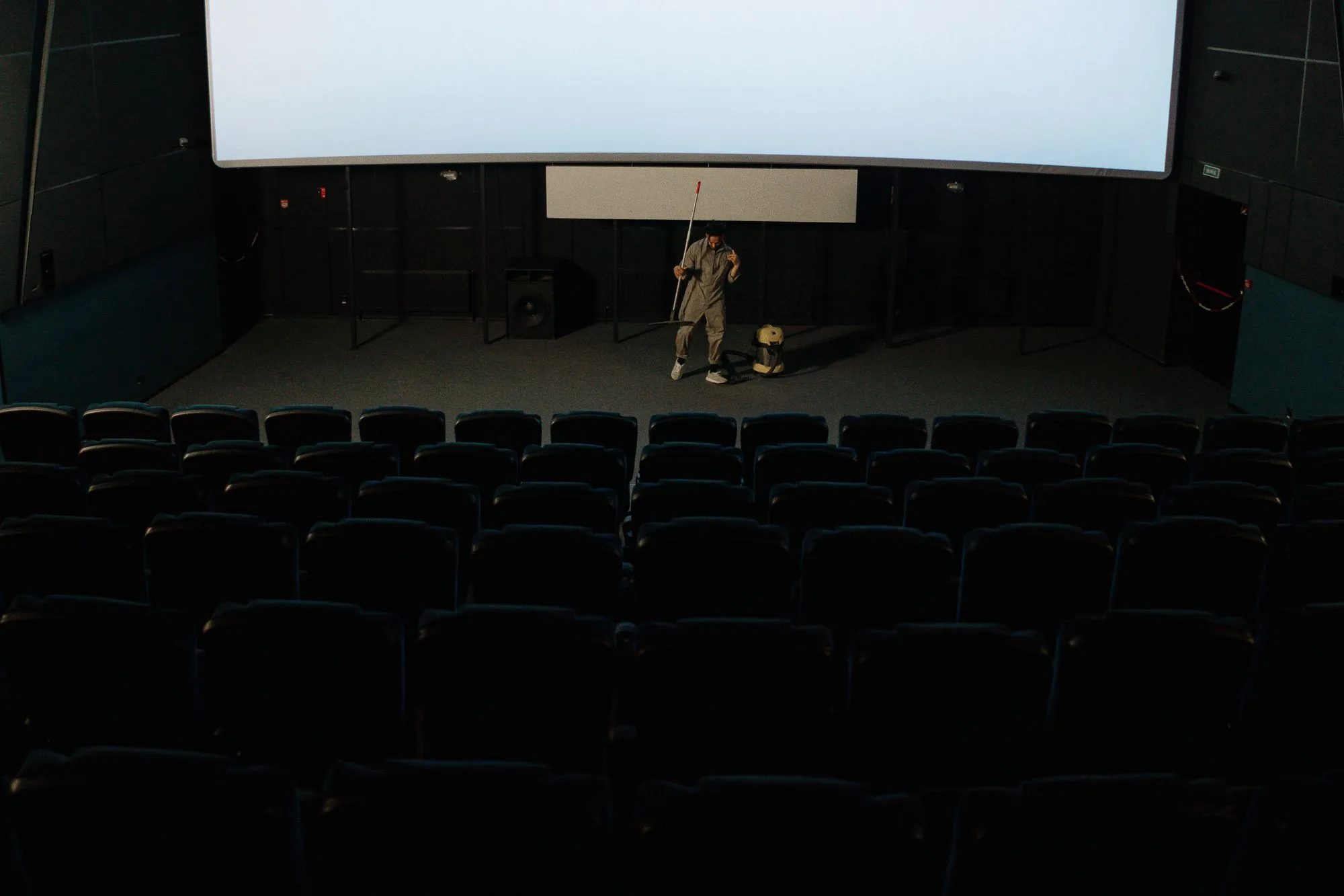 A lone crew member cleaning a large venue at night
